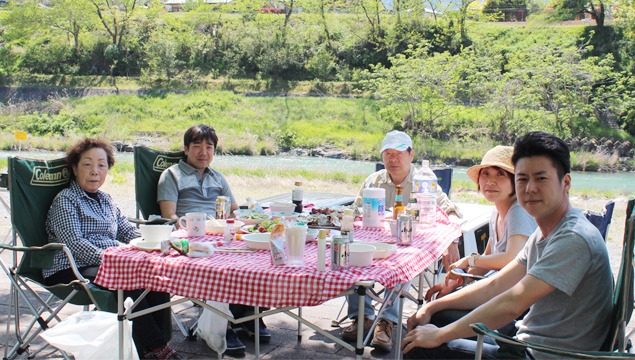 川を背にテーブルで食事を楽しむグループ